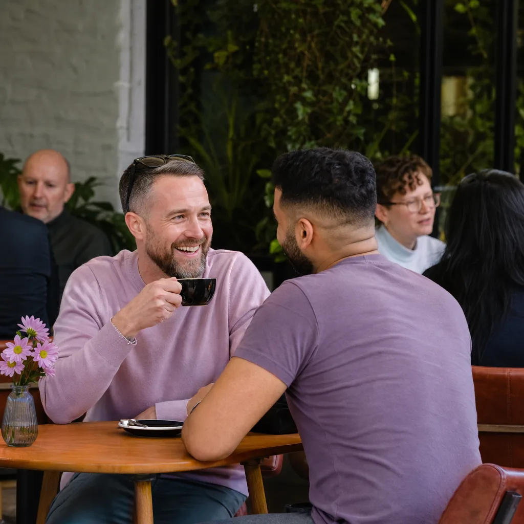 Man checking a dating profile on his phone in a busy Stoke-on-Trent café